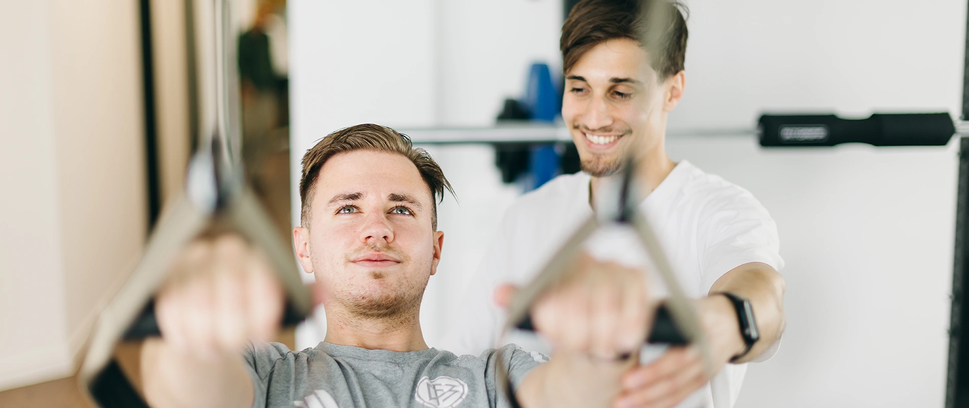 Ein Patient beim funktionellen Krafttraining am Seilzug unter Anleitung eines Sportphysiotherapeuten in der Praxis DuoLevitas.