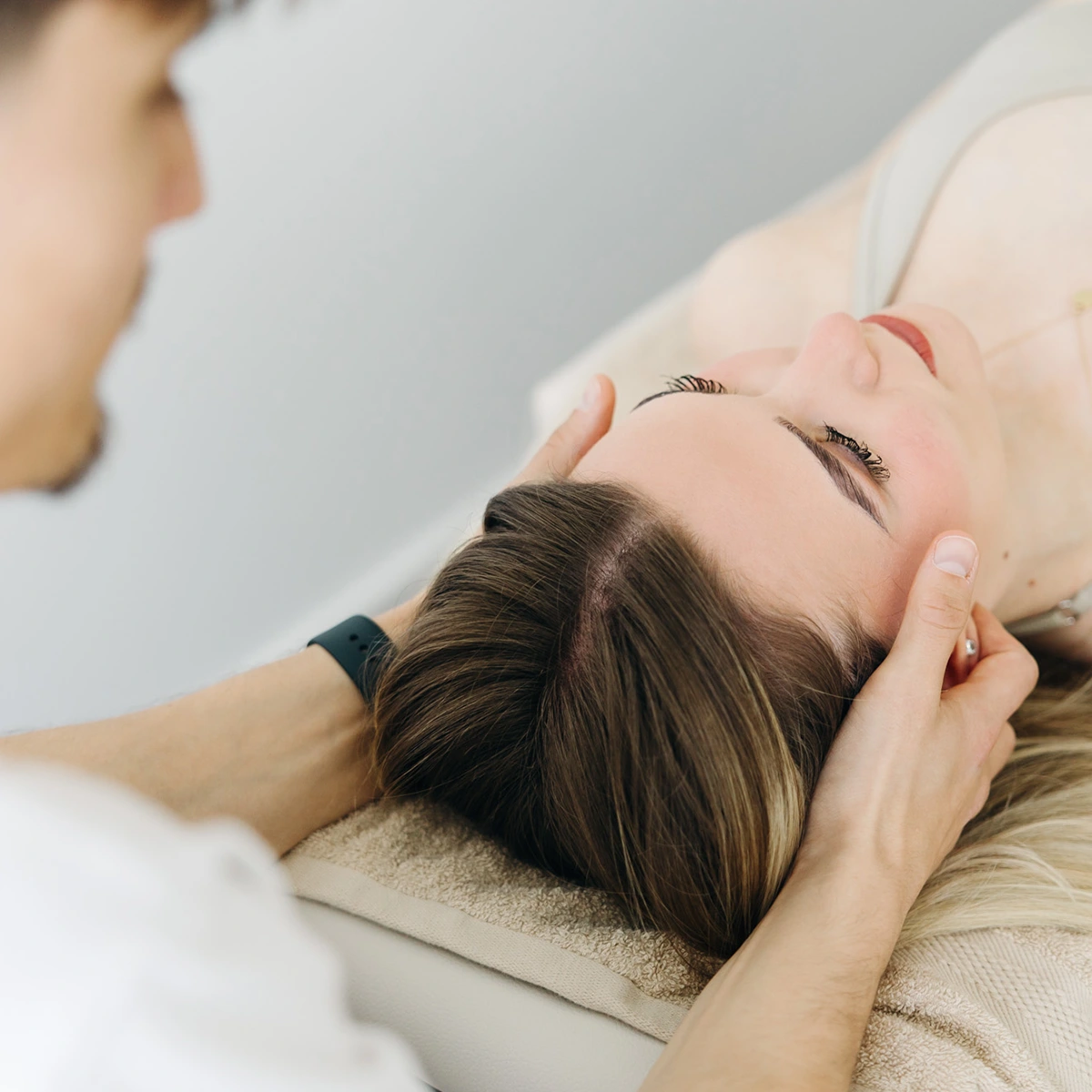 philosophie03 Nahaufnahme einer manuellen Behandlung am Nacken einer Patientin – Sportphysiotherapie und Rehabilitation in Oberhaching.